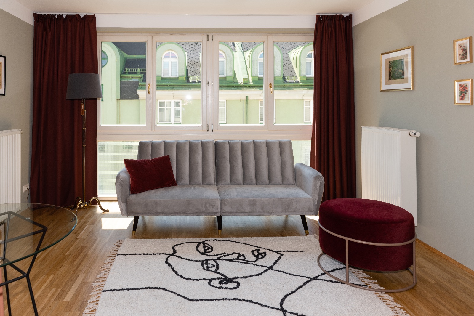 Appartement meublé à Vienne, chambre avec suspension et table d'appoint en laiton, entrée au papier peint de bouleau et salon avec canapé en velours gris