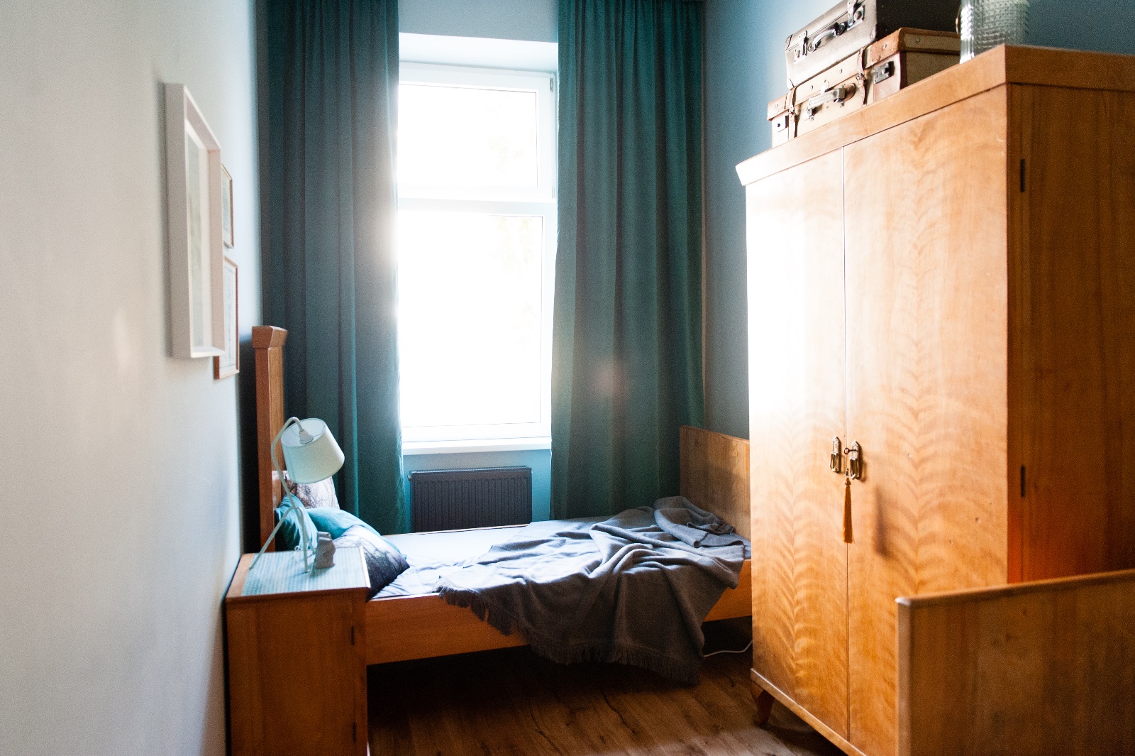 Living room with a light grey dining table on oak legs, a turquoise vintage cabinet and a pale sofa, alongside two bedrooms for a family living in Vienna for a while